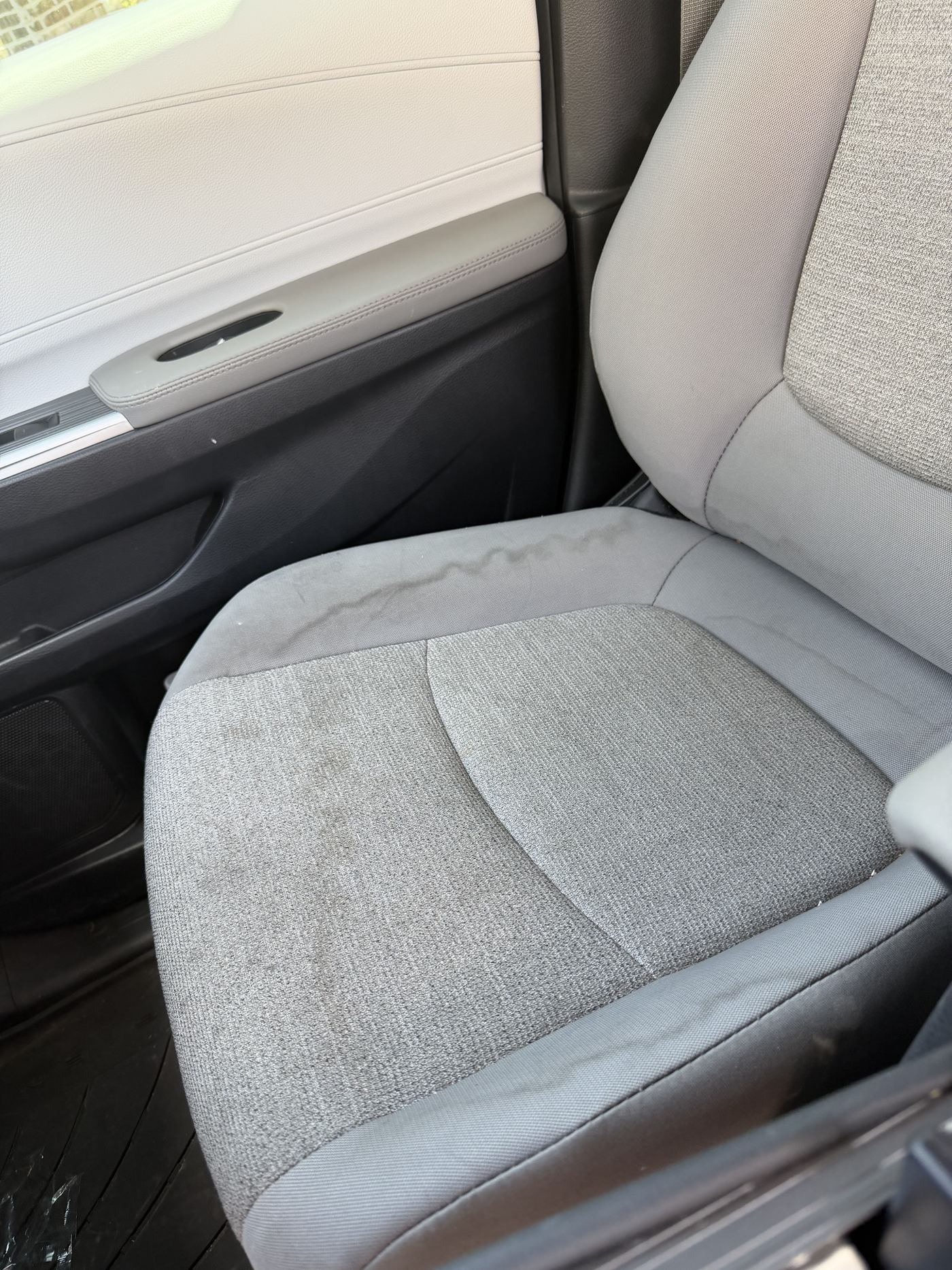 Fabric car seat marked with spills and ground-in dirt before detailing